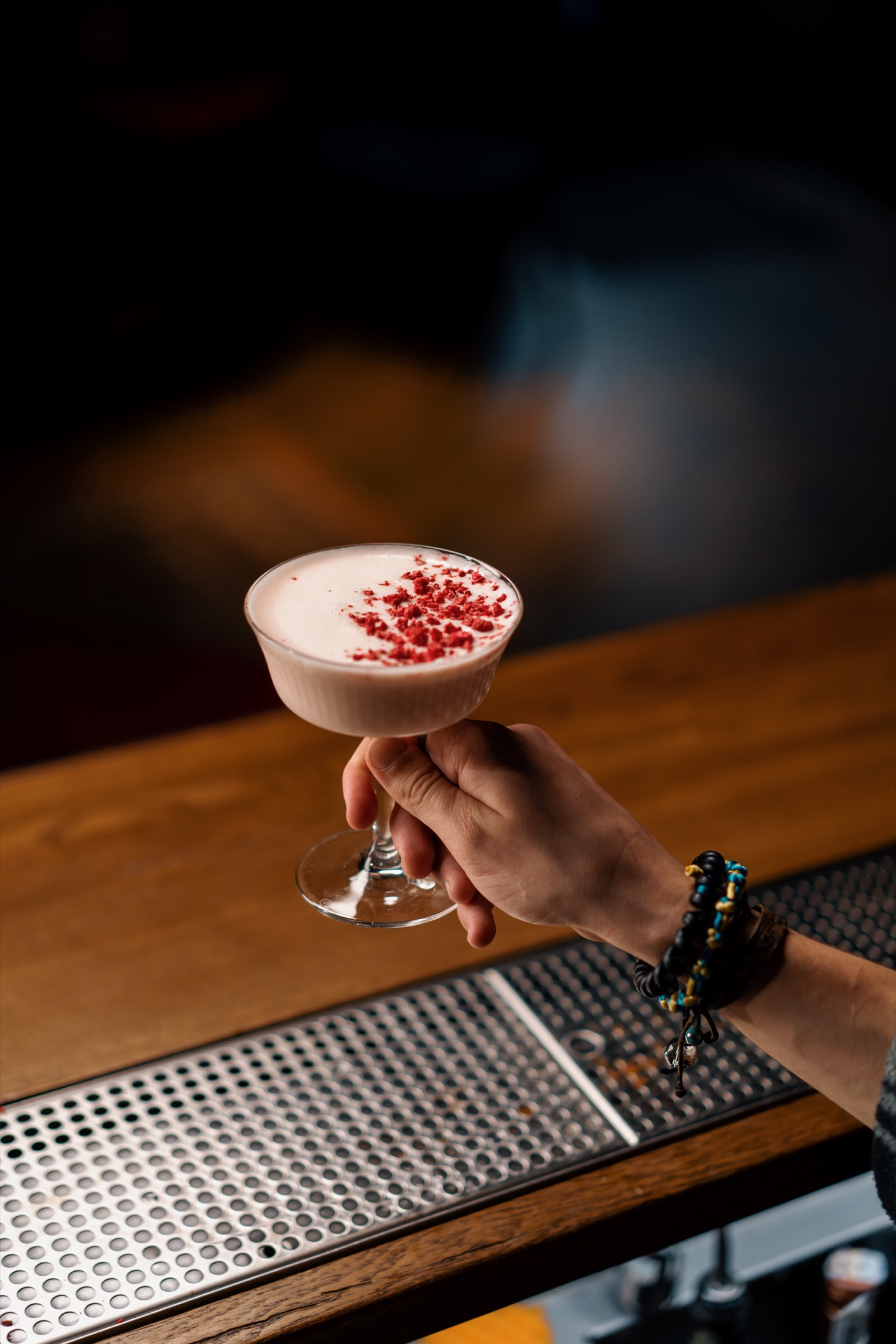 A close-up of a bar guest holding ready-made tasty bilberry club alcoholic cocktail in his hand