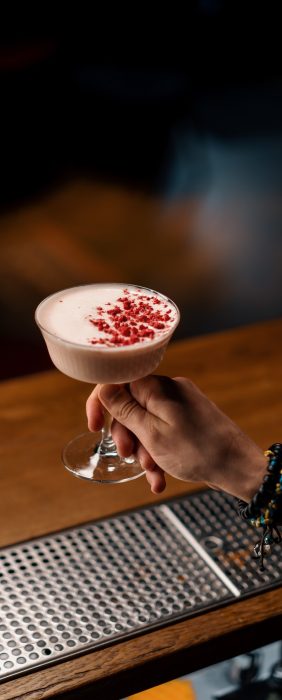 A close-up of a bar guest holding ready-made tasty bilberry club alcoholic cocktail in his hand